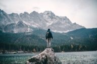 Uomo in piedi su una roccia sulla riva dell'Eibsee vicino a Garmisch, nella periferia di Monaco.