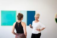 A gallery owner and a young woman talk in a gallery in Munich.