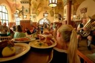 A waitress in the Hofbräuhaus in Munich is carrying traditional Bavarian dishes on a serving tray.