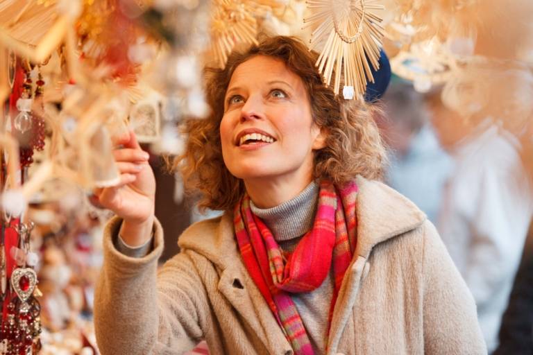 A woman with curly hair is eyeing decoration out of straw at a sales booth at the christmas market in Munich.