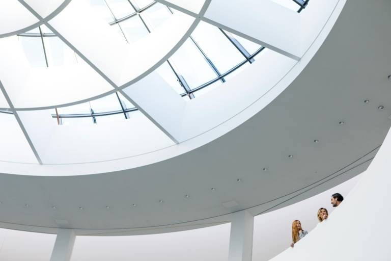 A family is standing in the highest floor of the Pinakothek der Moderne in Munich and is talking to each other.