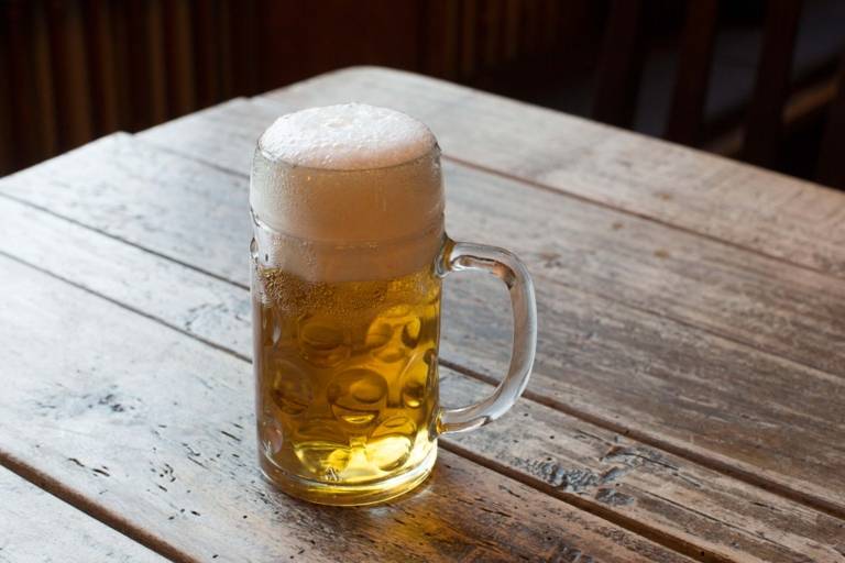 A pint of beer stands on a wooden table.