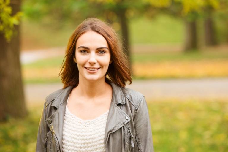 A young woman is smiling at English Garden in Munich.