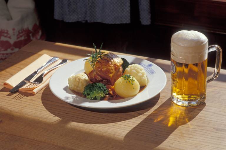 Beer and roast pork with dumpling on a wooden table