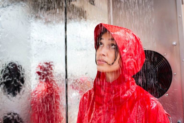 A woman is wearing a red rain jacket in the cold chamber of the store Globetrotter in Munich.