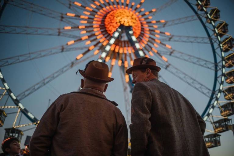 Two men in front of a ferris wheel at the Oktoberfest in Munich.