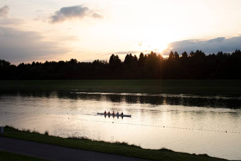 A rowing boat with five rowers in the evening light on the regatta course in Oberschleissheim near Munich.