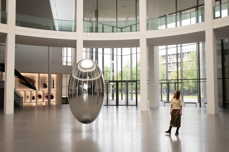 Une jeune femme se tient dans le hall d'entrée vide et lumineux d'un musée à Munich.