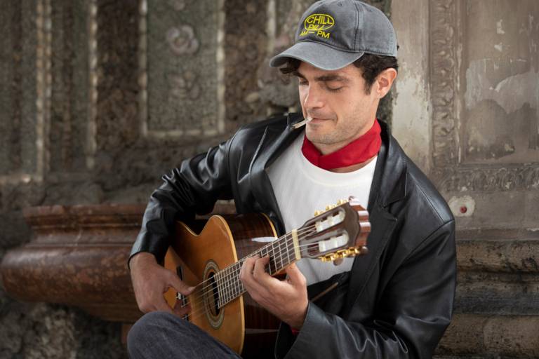 Italian guitarist Fausto Cassara smiling as he plays his instrument in Munich's Hofgarten.