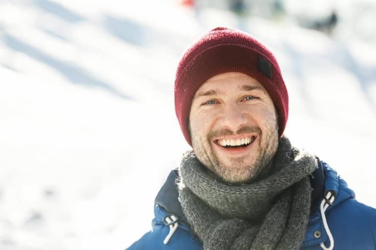 A man is wearing a red knitted hat on a winter day in Munich.