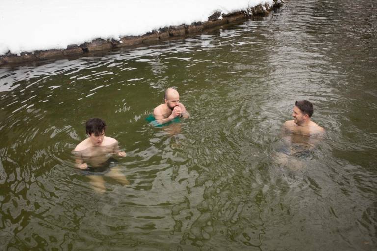 Three men ice bathing in the Eisbach in winter
