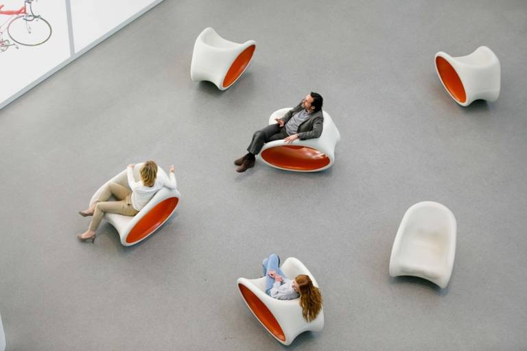 A family is sitting on chairs in front of a vitrine with exhibits in the Pinakothek der Moderne in Munich.