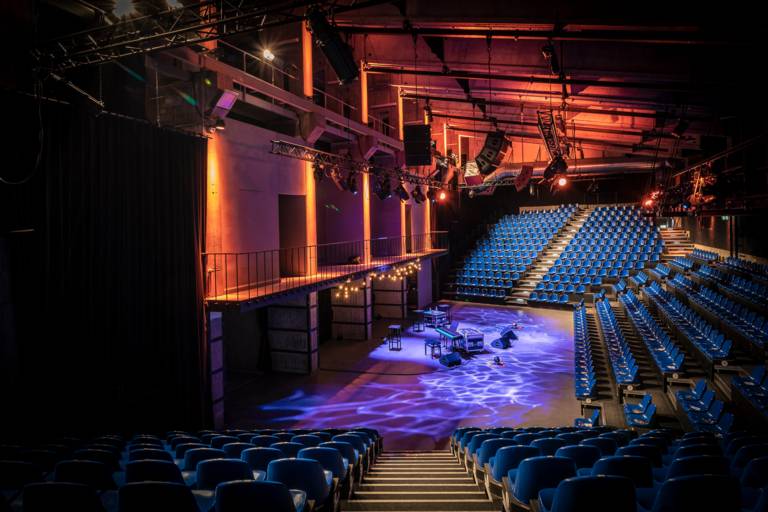 The inside of a theatre with stage and tiers without people