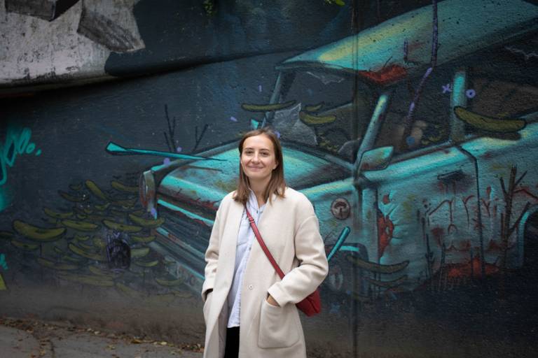 Young woman stands before a mural in Munich.