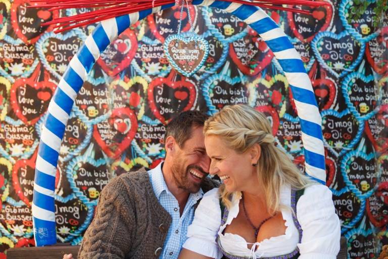 A couple is sitting in front of a lot of gingerbread hearts at the Oktoberfest in Munich.