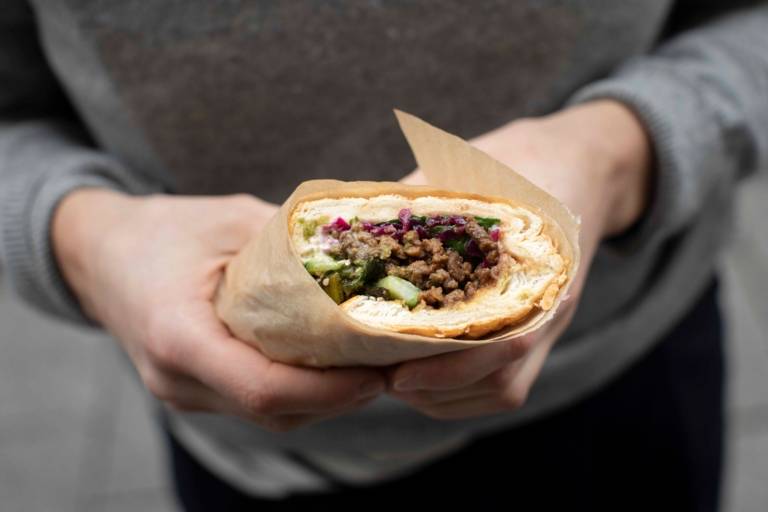 A woman holds a vegan sandwich in her hand