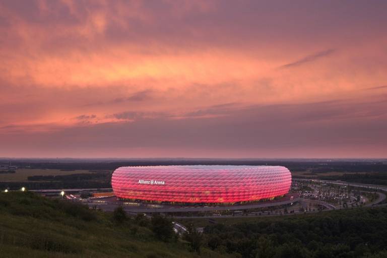 L'Allianz Arena à Munich brille de rouge dans la lumière du soir.