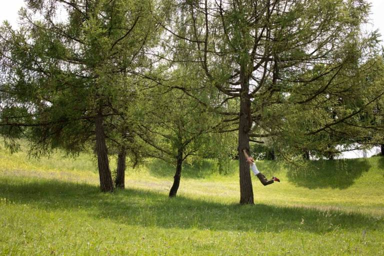 A woman swings with outstretched arms on a tree in Munich.