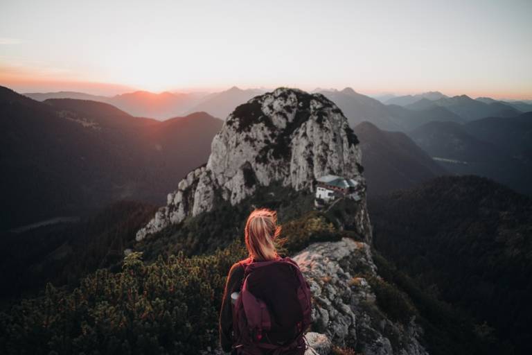 A woman with the Tegernseer chalet in the background at the Bavarian foothills of the Alps in the surrounding region of Munich.