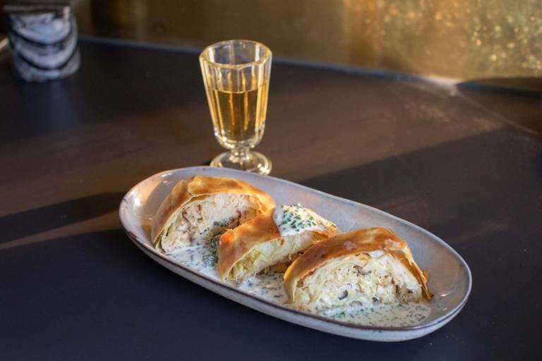 Krautrahmstrudel on a plate next to a glass of wine