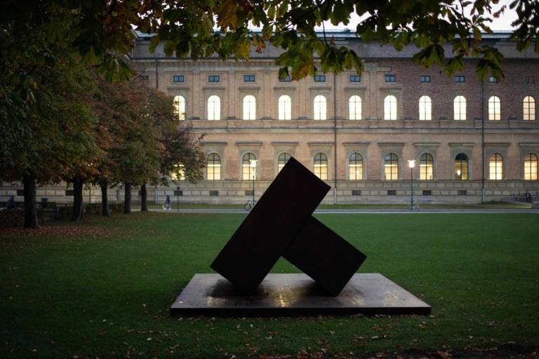 Vista frontal de la Alte Pinakothek con árboles y una escultura delante del edificio de Munich