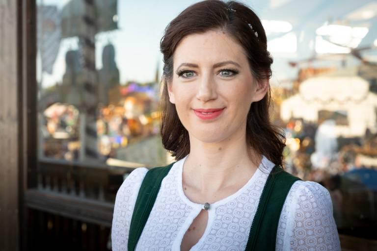 Cabaret artist Claudia Pichler stands in traditional costume on a balcony of an Oktoberfest tent.