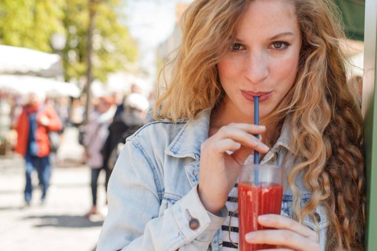 A woman is drinking a red smoothie at the Viktualienmarkt in Munich.