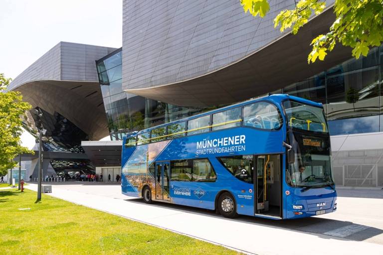 Un autobus turistico blu a due piani davanti al BMW Welt di Monaco.