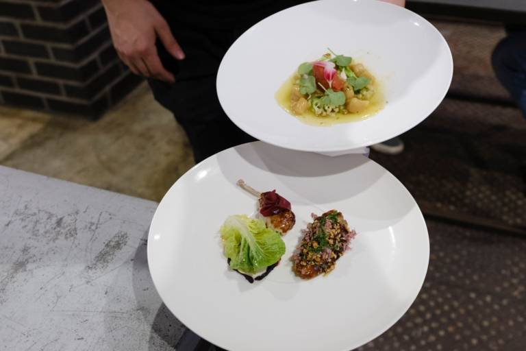 Two white plates with finely garnished small dishes in the Mural restaurant in Munich.