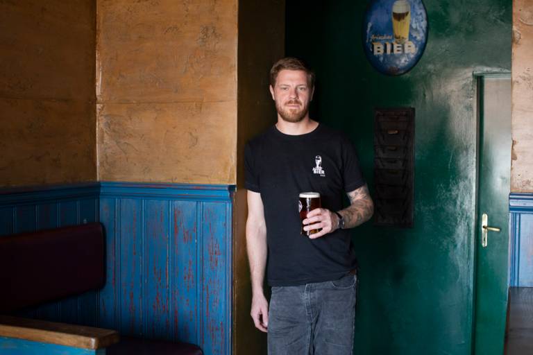 The founder of Tilmans Brewery, Tilman Ludwig, stands in a pub with a glass of beer