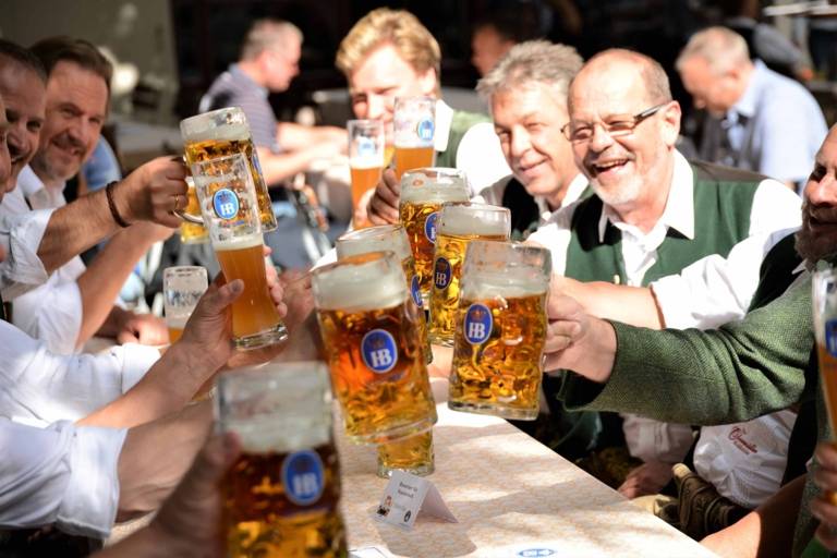 A table of men toasts each other in the beer garden of the Hofbräuhaus in Munich.