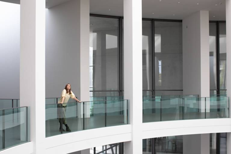 A young woman is standing in an empty museum in Munich.