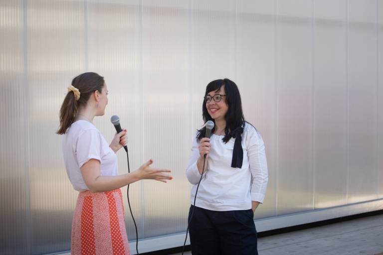 Two women talk to each other with microphones outside in Munich.