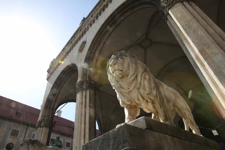 Statue of a marble lion flanking the steps of the Feldherrnhalle at Odeonsplatz in Munich.