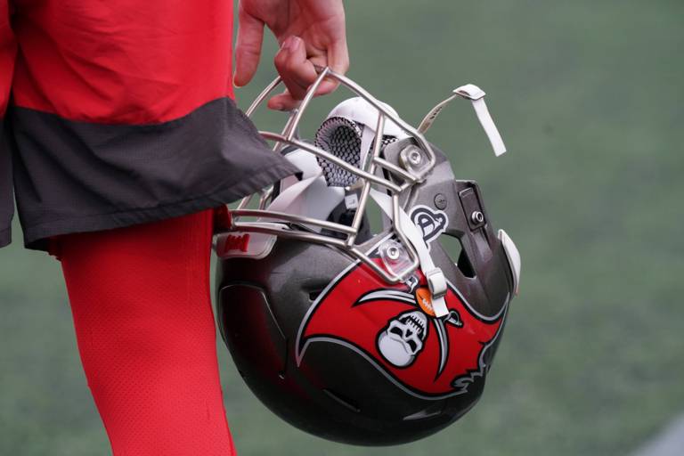 Detail of a player's hand holding a football helmet.