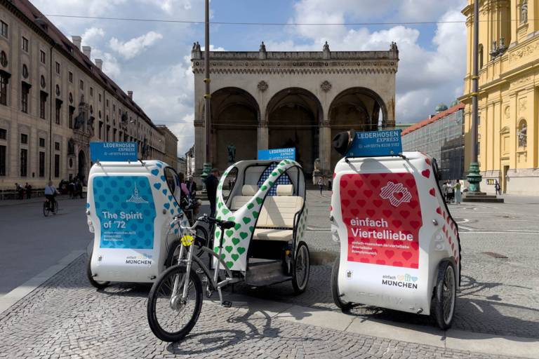 Three rickshaws from the Lederhosen Express company stand on Odeonsplatz in Munich.