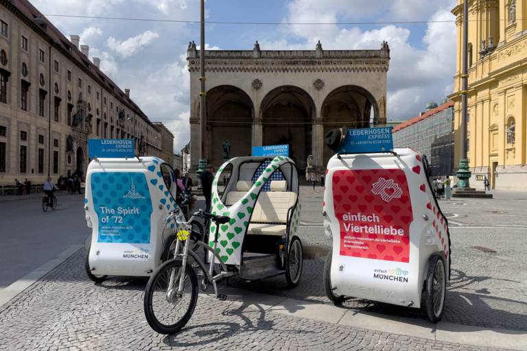 Trois pousse-pousse de la société Lederhosen Express se tiennent sur l'Odeonsplatz à Munich.