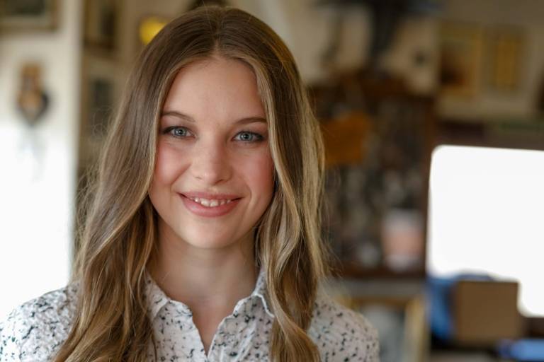 A young woman is smiling in the Valentin-Karlstadt-Musäum in Munich.