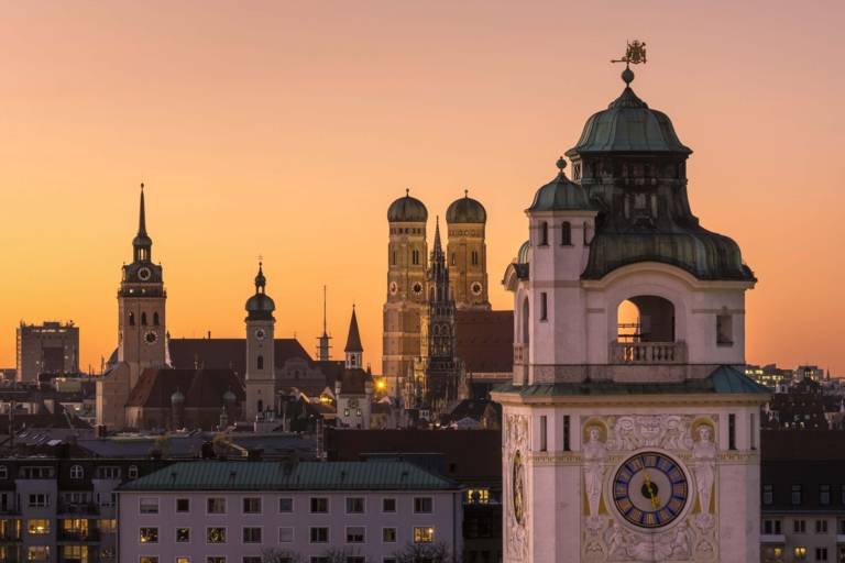 Vista panorámica del centro de Múnich al atardecer con el Müllerschen Volksbad en primer plano y las torres de Alter Peter, Heilig-Geist-Kirche y Frauenkirche al fondo.